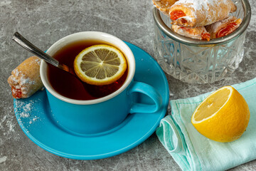 A cup of black tea with lemon on a granite glossy table