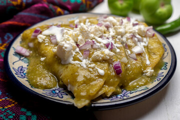 Green enchiladas with fresh cheese and sour cream on white background. Mexican food