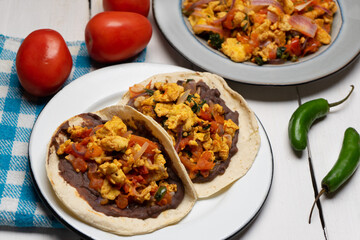 Scrambled eggs and refried beans tacos on white background. Mexican food