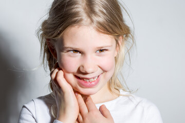 Portrait d'une enfant fille blonde avec ses mains au visage