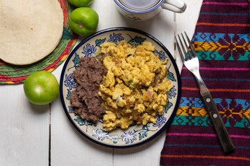 Scrambled eggs with green sauce and refried beans on white background. Mexican food