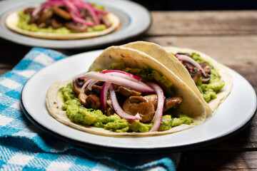 Mushroom and guacamole tacos on wooden background. Mexican food