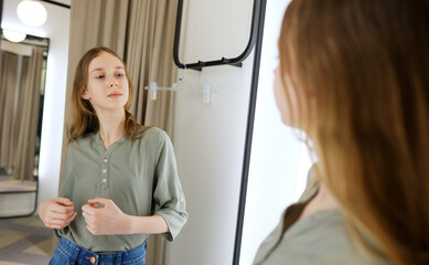 Tween girl standing in fitting room in clothing store.