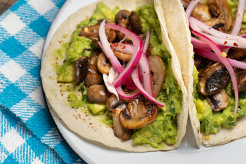Mushroom and guacamole tacos on wooden background. Mexican food