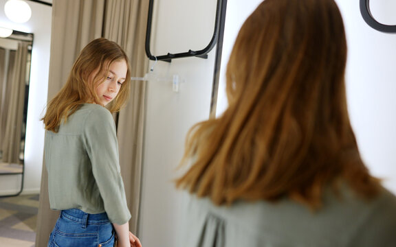 Tween girl standing in fitting room in clothing store.