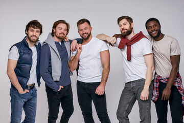 Fototapeta premium cheerful diverse men in casual urban style clothes posing at camera, stand together having talk and cmile, laugh. isolated white background
