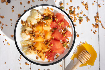Fruit salad with honey and yogurt on white background. Healthy food