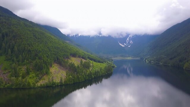 A soothing landscape on a calming river and huge mountains among forest tree. A sedative view of mountains, river, and forest