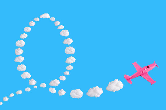 Pink airplane goes into a sharp turn on blue background and easter egg of abstract shapes of cloud. Festive minimal composition. Happy easter holiday concept, copy space 