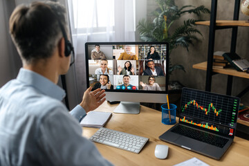 Fototapeta premium Online conference, video call. Successful adult businessman have conversation with multiracial business colleagues by video call using a computer while sitting at his workplace