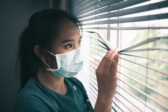 Asian female healthcare worker doctor nurse surgeon wearing protective surgical mask corona covid-19 virus prevention, feeling worried anxious anxiety traumatized scared, medical stress at hospital