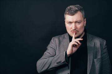 Confidential information, silence concept. Portrait of a serious business man showing silence gesture