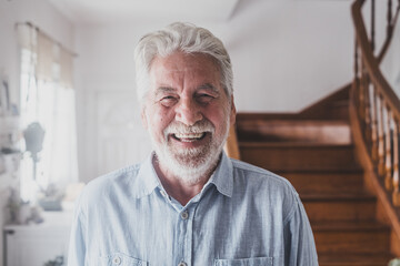 Portrait of old man smiling and looking at the camera having fun indoor at home. Closeup male person senior cheerful indoor.
