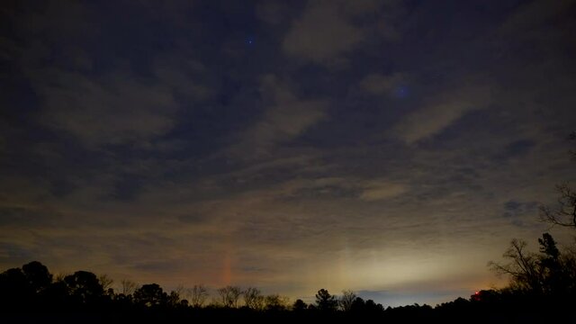 Light pillars, clouds and stars rising over trees in Mount Gilead, timelapse