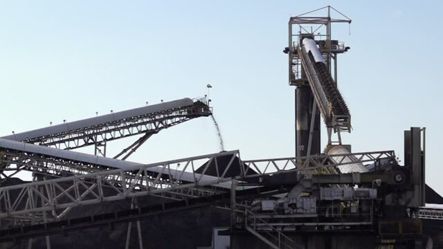 Slow Motion Extreme Wide Shot of Coal flying off Conveyer into large Pile of Coal with other Conveyer Belt in the foreground in North America stock footage