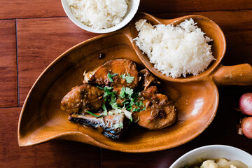 Beautiful wooden plate is serving a Vietnamese dinner with a food dish called " Ca Kho To " (Caramelized Fish) served with white rice