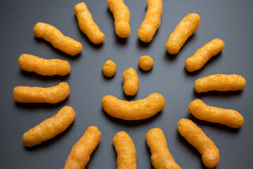 Cheese puffs flat lay, Cheese Doodle Day, symbol of the sun made of crisps