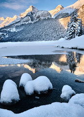 Frozen alpine lake and mountains glowing in dawn light. Iconic Lake Louise. Banff National Park. Alberta. Canada