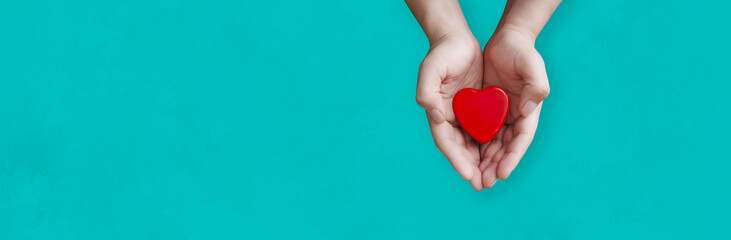 Obraz premium person holding a heart in his hands with blue background