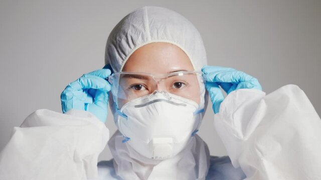 Closeup hand of woman doctor or scientist in PPE suite uniform wearing blue glove protective wear medical face mask and protective glasses coronavirus or COVID-19 healthcare medical concept