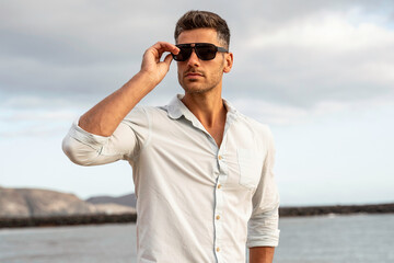 Gorgeous stylish man wearing fashionable shirt and sunglasses. City style. - Powered by Adobe