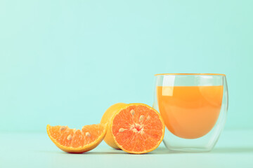 Fresh tangerine orange fruit and juice in glass on color background
