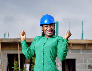 A Nigerian female construction and architectural engineer with blue safety helmet jubilating  