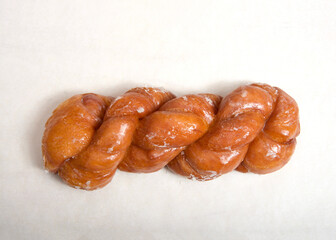 Flat lay top view of one glazed twist cinnamon rolls on parchment paper.