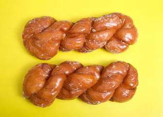 Flat lay top view of two glazed twist cinnamon rolls. Bright yellow background.