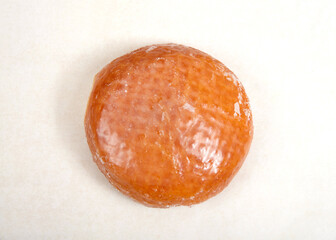Flat lay top view of one glazed jelly donut on parchment paper.