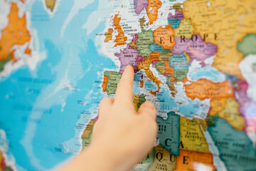 Fototapeta na wymiar Human woman man hand pointing out to Europe country on map. Travel dream destination. France country landmark on a world global colorful map. Dreaming about travelling and crossing borders.