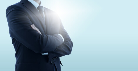 Confident business manager with crossed arms. Pale blue background with backlit.