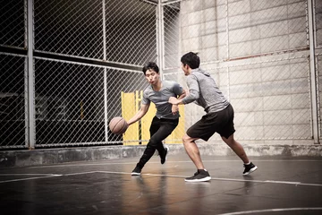 Fotobehang two young asian men playing basketball outdoors © imtmphoto