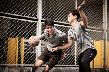 two young asian men playing basketball outdoors