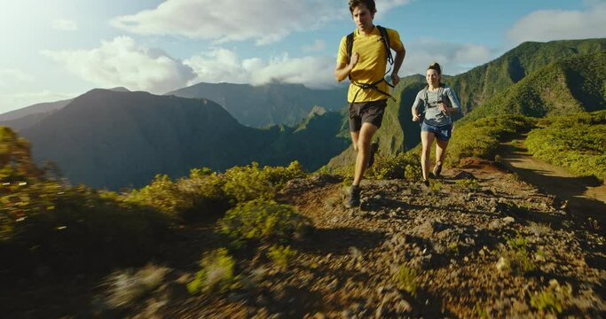 Adventure couple running on epic mountain trail at sunset, healthy active lifestyle, trial running marathon training