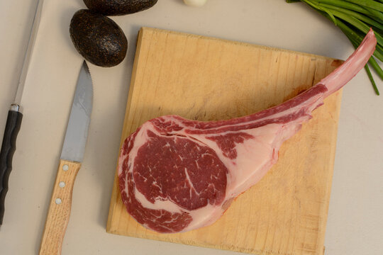 corte de carne tomahawk crudo sobre una tabla para cortar. concepto de carne asada