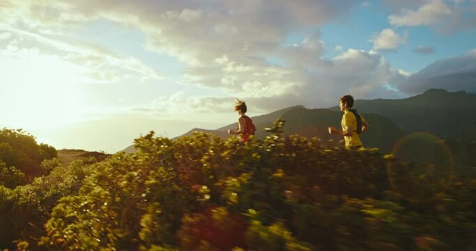 Athletic man and woman running on mountain trail at sunset, healthy fitness lifestyle. Jogging on trail, Shot on RED cinematic slow motion