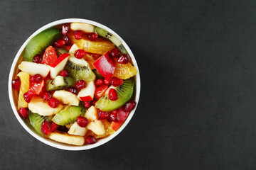 Fresh fruit salad cup made of juicy fruits on a black background.
