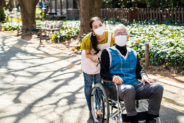 ウイルス感染対策をした介護士の女性と車椅子の高齢男性