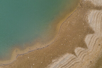 Aerial top view pattern of clear river water and sand on the river bank