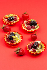 Tartles with fruits and berries on red background