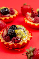 Tartles with fruits and berries on red background