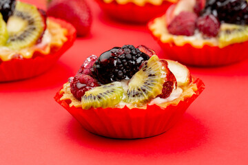 Tartles with fruits and berries on red background