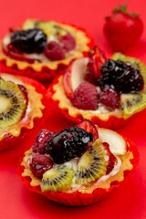 Tartles with fruits and berries on red background