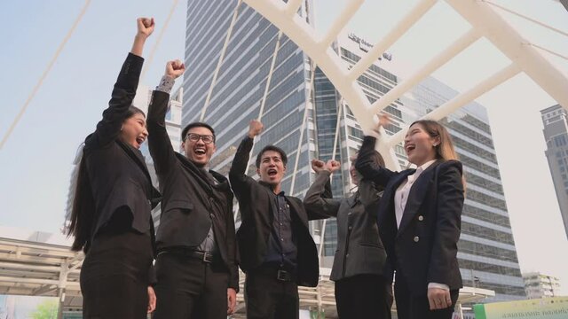 Group of business people in suit standing and putting hands together after successful meeting in city. Successful teamwork of happy business man and woman join hands in outdoors on city background. 