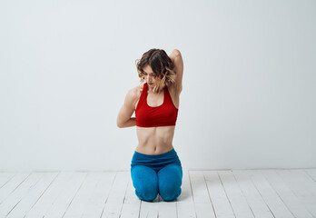 A woman in sportswear is doing yoga in a bright room and gesticulating with her hands