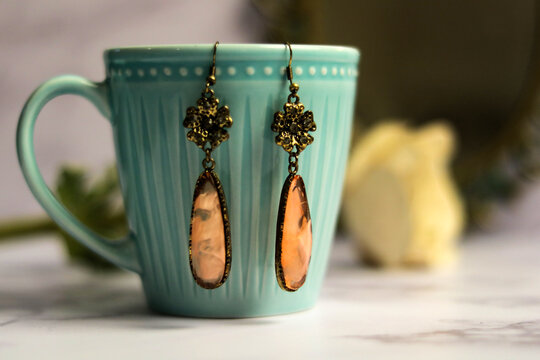 Zarcillos rosados largos sobre taza turquesa