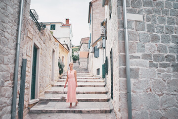 Traveling by Europe. Happy young woman in elegant dress walking by streets in Split, Croatia.