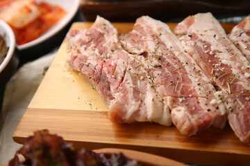 밑반찬과 생돼지고기가 있는 상차림 Table set with side dishes and raw pork