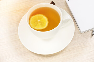 Close-up of a white cup with lemon tea on the background of a notebook.